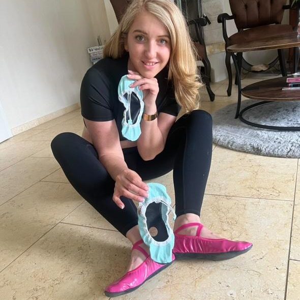 Iwona unsere Produkttesterin der ersten Stunde in Sportkleidung zeigt Ballettschuhe in der Hand und trägt pinke Ballettschuhe.